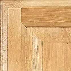 Close-up of a light-colored wooden cabinet door corner, showing grain and beveled edges.