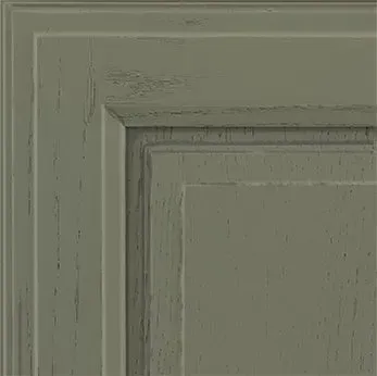 Distressed gray-green cabinet door corner with layered panels and textured finish.