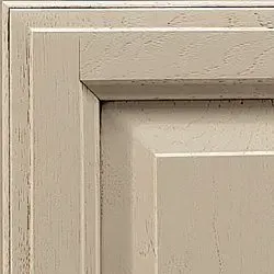 Close-up of a light-colored, distressed wooden cabinet door corner.