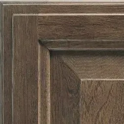 Close-up of a brown wooden cabinet door showing raised panel and wood grain details.