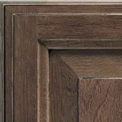 Close-up of dark brown wooden cabinet corner with recessed panel and decorative trim.