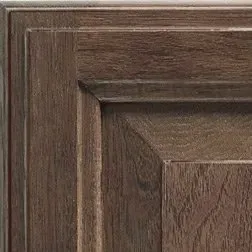 Close-up of a wood cabinet door with a rectangular panel and detailed trim, in shades of brown.