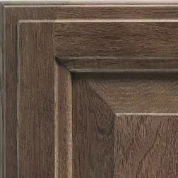 Close-up of a dark brown wooden cabinet door with a raised panel and detailed trim.