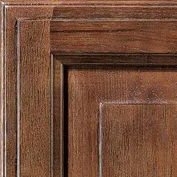 Close-up of dark wood cabinet door, showing grain and layered trim detail.