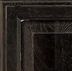 Close-up of dark stained wooden cabinet door with recessed panel and layered frame.