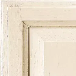 Close-up of a white painted cabinet door with visible wood grain and distressed finish.