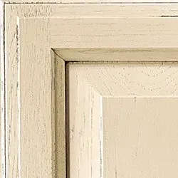 Cream-colored distressed cabinet door corner detail.