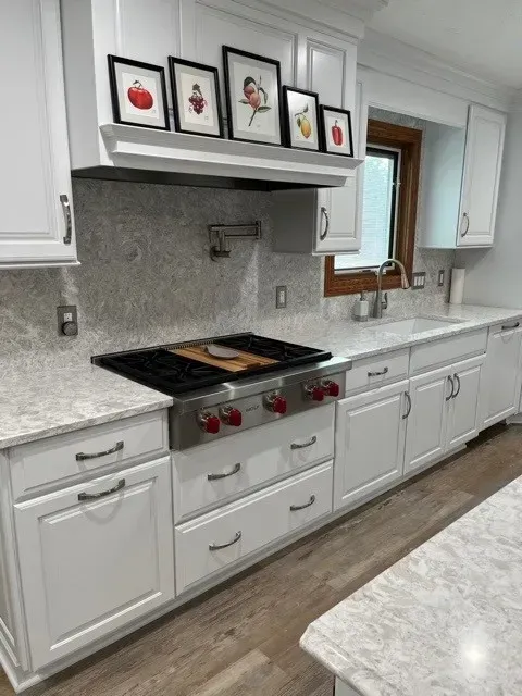 White kitchen with stainless steel appliances, white cabinets, and colorful framed art.