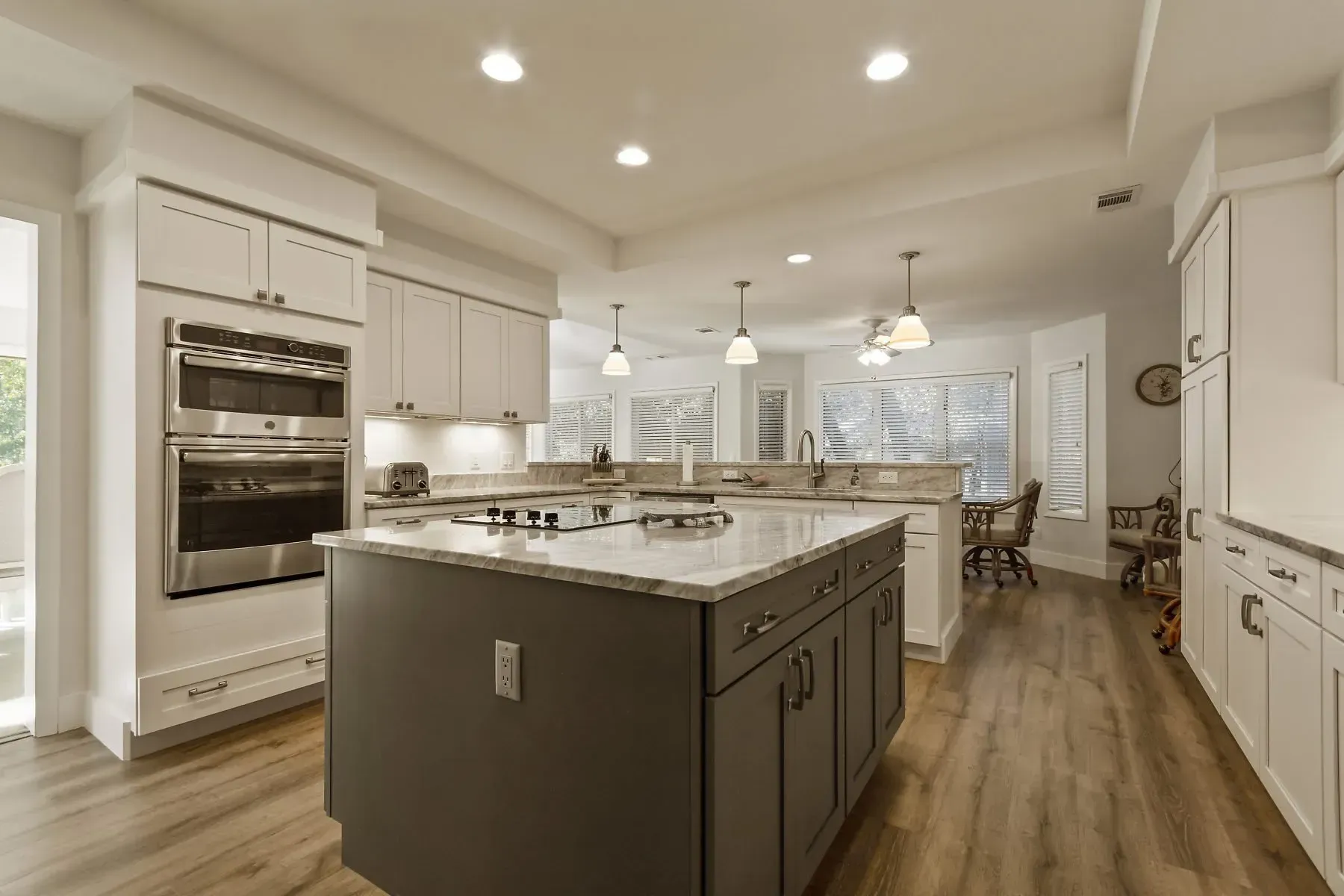 Modern kitchen with gray island, white cabinets, and wood floors.