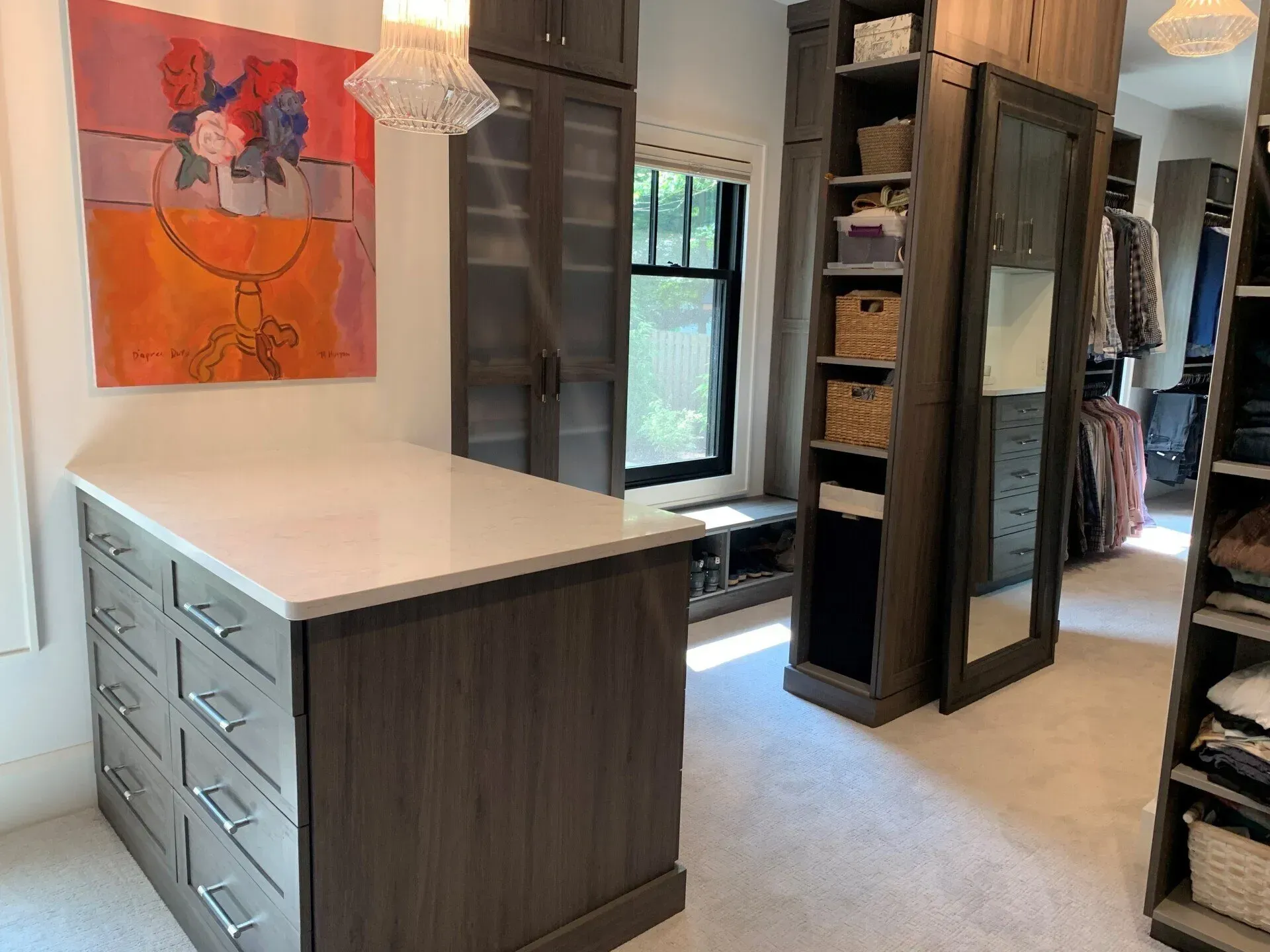 Walk-in closet with drawers, shelves, a window, and a colorful painting on the wall.