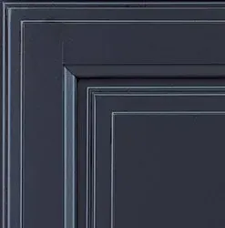 Close-up of a dark blue cabinet door corner, with layered trim details and white accent lines.
