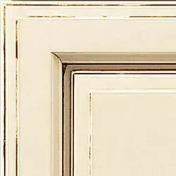 Off-white cabinet door corner with gold and brown trim.