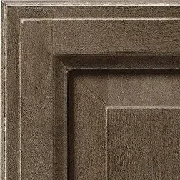 Corner of a textured, dark brown cabinet door with rectangular panels and layered details.