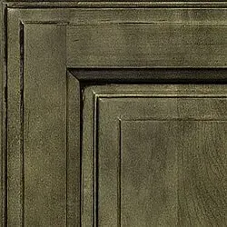 Close-up of a wooden cabinet door corner, distressed olive green finish with recessed paneling.