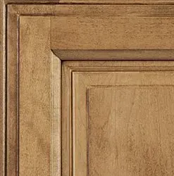 Close-up of a wooden cabinet door with a light brown finish and raised panel.