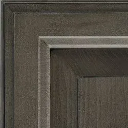 Close-up of a gray-brown wooden cabinet door with raised panel and decorative trim.