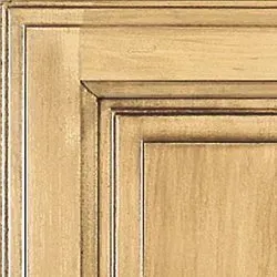 Close-up of a cabinet door with a distressed, light wood finish and detailed paneling.