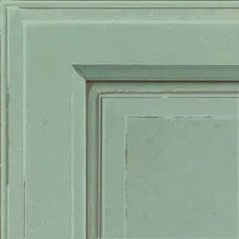 Close-up of a painted cabinet door corner, a muted teal green with distressed edges.
