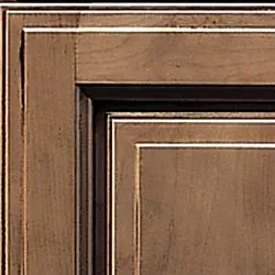 Corner of a wooden cabinet door; brown stain with a light-colored highlight and a recessed panel.