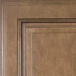 Close-up of a brown, raised-panel cabinet door with decorative trim.