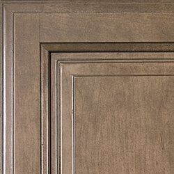 Close-up of a wooden cabinet door with a light brown finish and recessed panel.