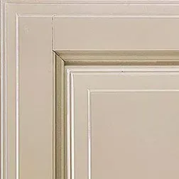 Corner of a cream-colored cabinet door with raised panel and molding details.