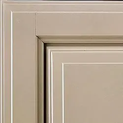 Close-up of a beige cabinet door showing the panel and frame construction with a slight texture.