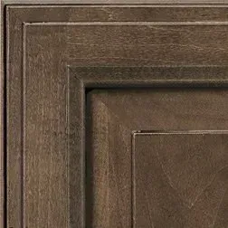 Close-up of a dark brown cabinet door with recessed paneling and wood grain texture.