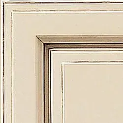 Corner of a painted cream cabinet door with brown and silver trim.