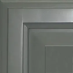 Corner of a gray cabinet door with recessed panel and trim.