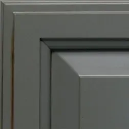 Gray cabinet door corner, with visible wood grain and raised panel.