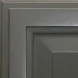 Close-up of gray kitchen cabinet corner, with recessed panel and layered trim.