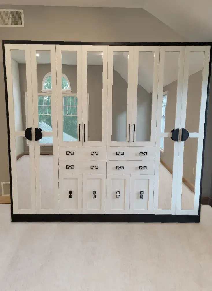 White and mirrored wardrobe with black trim against a gray wall.