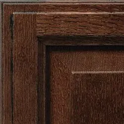 Close-up of a dark stained wood cabinet door with raised panel and wood grain texture.