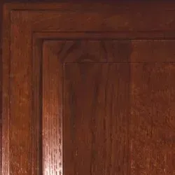 Close-up of a dark wooden cabinet door with a raised, rectangular frame.