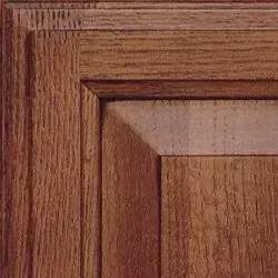 Close-up of a wooden cabinet door with a raised panel, stained in a reddish-brown hue.