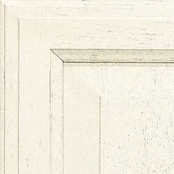 Close-up of a painted white cabinet door corner, showing textured wood grain and a beveled edge.