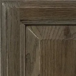 Close-up of a wooden cabinet door with a weathered, gray-brown finish and visible wood grain.