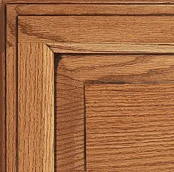Corner of a wooden cabinet door showing a raised panel, stained in shades of brown.