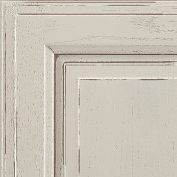 Close-up of a weathered, off-white kitchen cabinet door with framed paneling.
