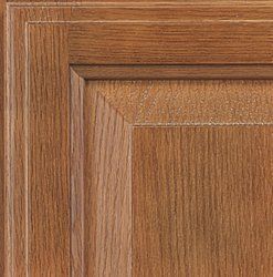 Close-up of wooden cabinet door, showing raised panel with visible wood grain in shades of brown.