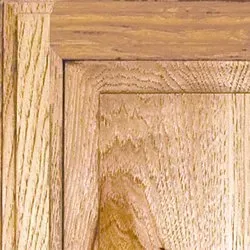 Corner detail of light-colored wood paneling with visible grain, showing trim and frame.