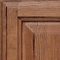 Close-up of a stained oak cabinet door with raised panel and wood grain detail.