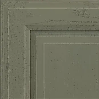 Close-up of a painted wooden cabinet corner in a muted green color with distressed finish.