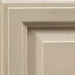 Close-up of a light beige, paneled cabinet door with wood grain texture and a recessed center.