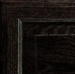 Close-up of a dark brown wood cabinet door corner, showing textured grain and molded trim.