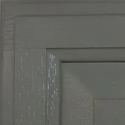 Gray-painted cabinet door corner, with square panels and beveled edges.