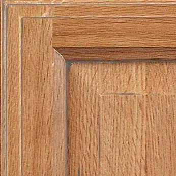 Close-up of a wooden cabinet door corner, showing natural wood grain and a raised panel design.