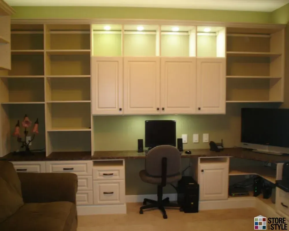 Built-in home office with white cabinets, desk, shelving, and a computer.