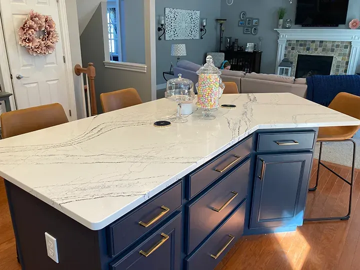 Navy blue kitchen island with white countertop, gold hardware, and candy jars.